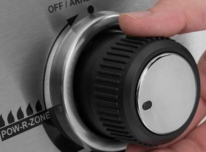 Close-up of hand adjusting the control knob on Broil King CROWN 520 grill featuring professional-grade performance and durable design